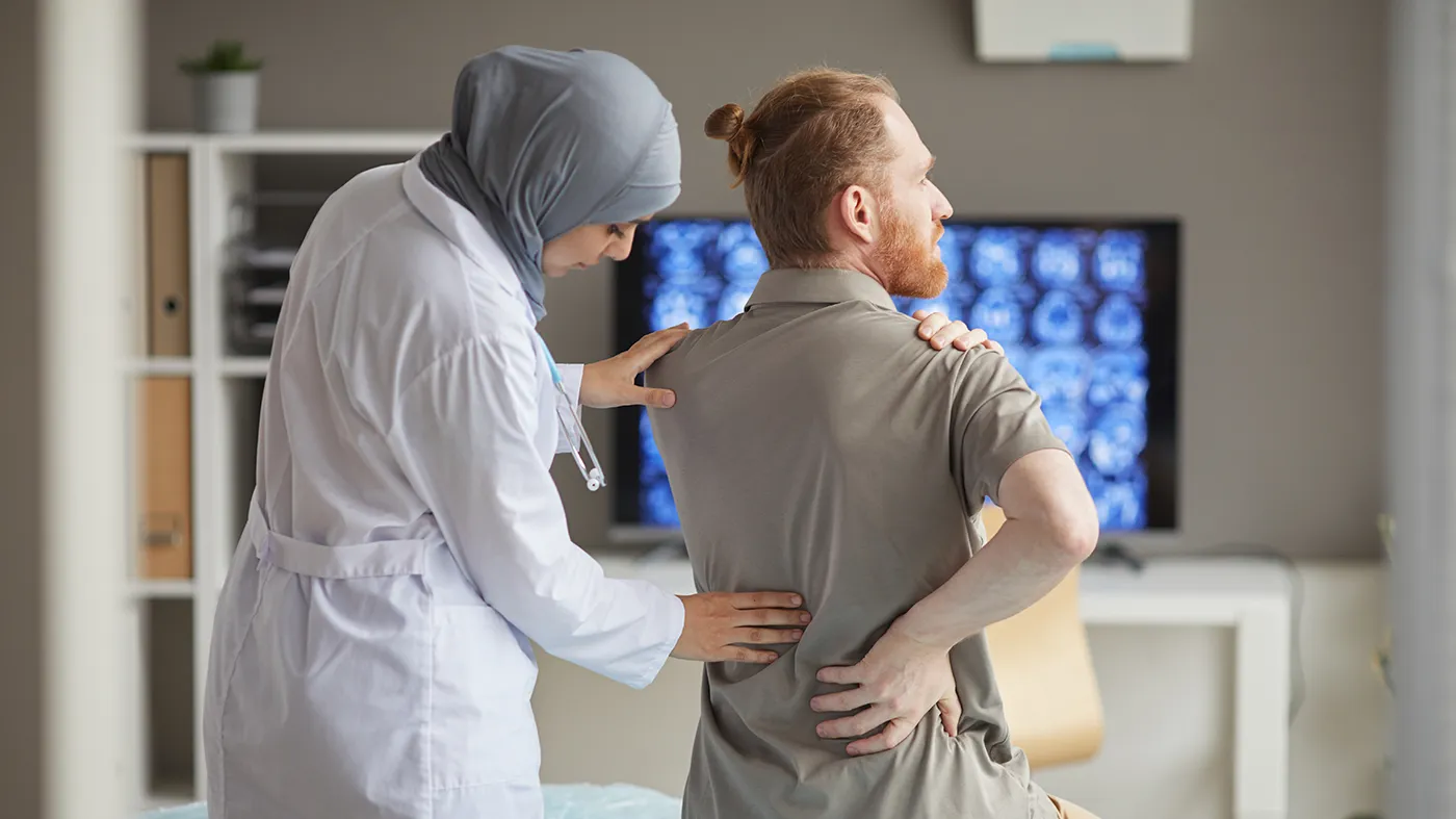 Doctor evaluating patient with physical discomfort, representing multiple sclerosis symptoms and clinical trials available nationwide through Equity Medical