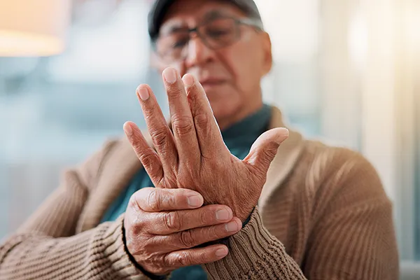 Close-up of elderly patient supporting their hand, highlighting motor symptoms in Parkinson's clinical trials with nationwide access at Equity Medical