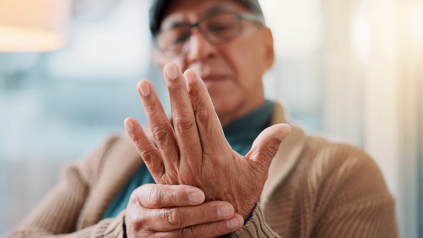 Elderly patient holding hand due to stiffness and motor symptoms, representing Parkinson's clinical trials and nationwide access through Equity Medical