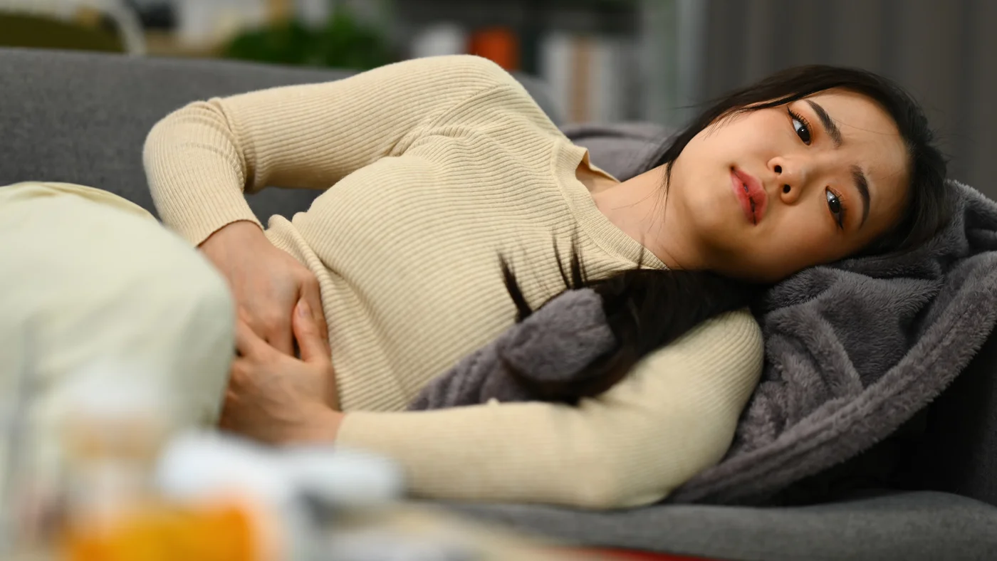 Woman resting at home while experiencing pelvic pain associated with endometriosis symptoms.
